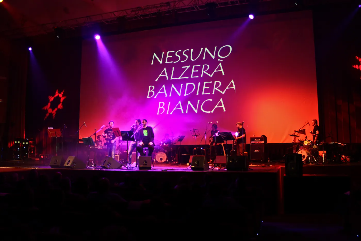 Il Fante in concerto davanti alla scritta “Nessuno alzerà bandiera bianca”